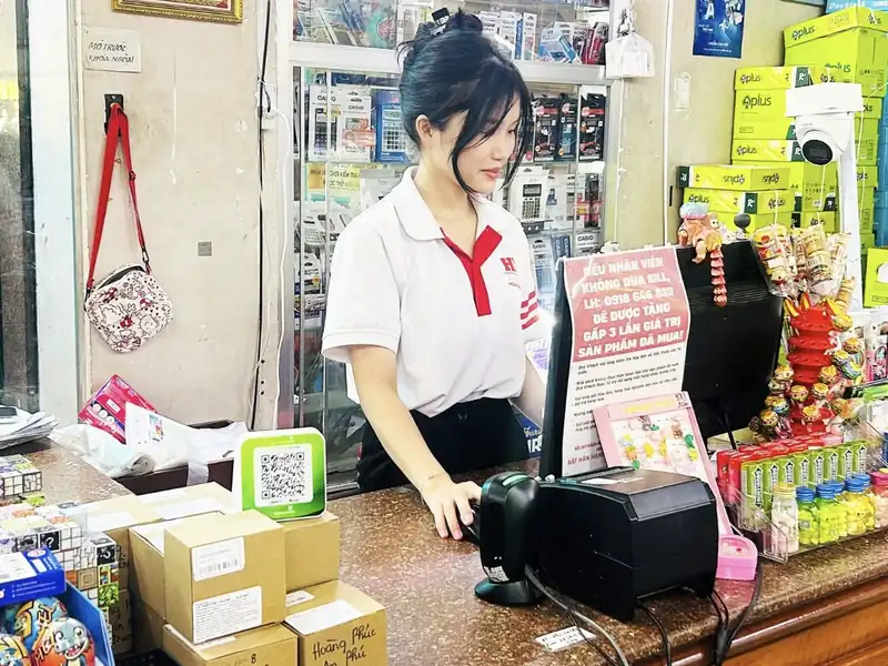 Nhân viên Nhà sách Hoàng Phúc tại quầy thu ngân, cạnh chiếc Loa X Vietcombank