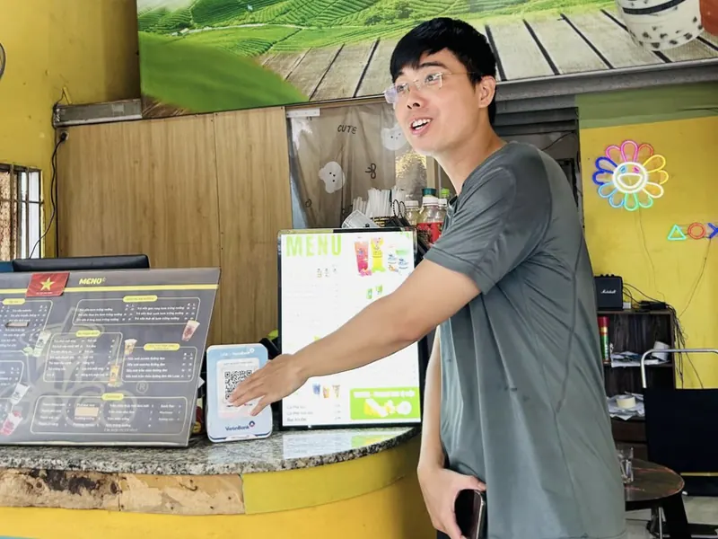 Anh Tuyền chỉ vào bảng QR Loa X VietinBank tại quầy trà sữa Higogo